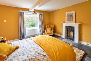 Finest Retreats - Islip Mill House - Beautiful Riverside Home في Islip: غرفة نوم صفراء مع سرير ومدفأة