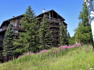 a building on a hill with a field of flowers at Studio coin montagne à Risoul 1850 - FR-1-330-541 in Risoul