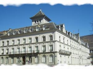 un grand bâtiment blanc avec une tour d'horloge en haut dans l'établissement Studio Bagnères-de-Luchon, 1 pièce, 3 personnes - FR-1-313-163, à Luchon