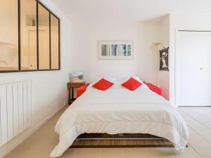 um quarto branco com uma cama grande e almofadas vermelhas em Studio Saint-Jean-de-Luz, 1 pièce, 2 personnes - FR-1-4-596 em Saint-Jean-de-Luz