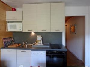 une cuisine avec des armoires blanches et un appareil noir dans l'établissement Appartement Le Grand-Bornand, 3 pièces, 6 personnes - FR-1-458-90, au Grand-Bornand