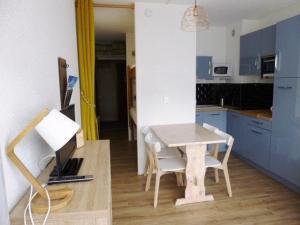a kitchen with a table and chairs and a kitchen with blue cabinets at Studio Arette, 1 pièce, 4 personnes - FR-1-602-58 in Arette