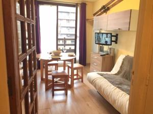 ein Wohnzimmer mit einem Sofa, einem Tisch und einem TV in der Unterkunft Appartement Risoul, 1 pièce, 4 personnes - FR-1-330-518 in Risoul
