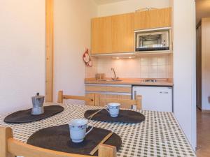 una cucina con tavolo e due tazze sopra di Appartement Montgenèvre, 1 pièce, 3 personnes - FR-1-330D-117 a Monginevro
