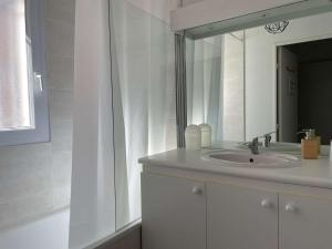 een witte badkamer met een wastafel en een spiegel bij Appartement Banyuls-sur-Mer, 3 pièces, 6 personnes - FR-1-225C-88 in Banyuls-sur-Mer