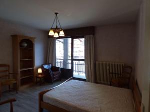 1 dormitorio con 1 cama, 1 silla y 1 ventana en Maison Le Grand-Bornand, 3 pièces, 6 personnes - FR-1-458-96, en Le Grand-Bornand