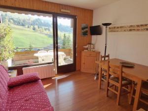 uma sala de estar com uma mesa e uma varanda em Appartement Le Grand-Bornand, 3 pièces, 6 personnes - FR-1-458-93 em Le Grand-Bornand