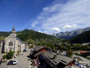 a small town with a church and mountains in the background at Maison Le Grand-Bornand, 3 pièces, 6 personnes - FR-1-458-96 in Le Grand-Bornand