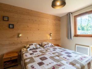 ein Schlafzimmer mit einem Bett mit einer Holzwand in der Unterkunft Charmant T2 avec parking à Valmorel - FR-1-291-867 in Valmorel