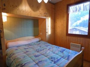 een bed in een houten kamer met een raam bij Appartement Le Grand-Bornand, 2 pièces, 6 personnes - FR-1-458-139 in Le Grand-Bornand