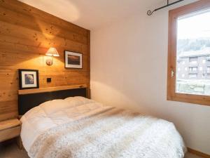 Un dormitorio con una cama con una pared de madera. en Bel appartement rénové, 4 pers, balcon, casier à skis - FR-1-291-865, en Valmorel