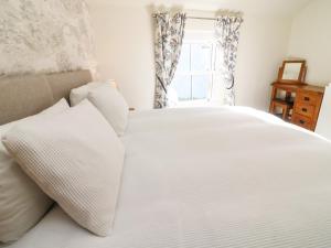 a white bed with white pillows and a window at 1A Lower Croft Street in Settle