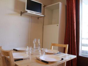 a table with plates and glasses on it with a television at Appartement Risoul, 2 pièces, 4 personnes - FR-1-330-525 in Risoul