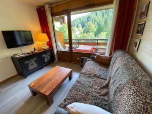 a living room with a couch and a table and a television at Appartement Le Grand-Bornand, 1 pièce, 3 personnes - FR-1-241-238 in Le Grand-Bornand