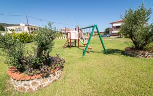a playground with a swing and flowers in a yard at Anthemida Rooms in Sykia Chalkidikis