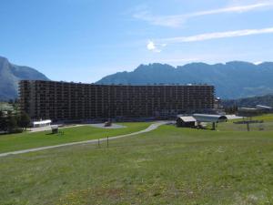 un grande edificio in un campo con montagne sullo sfondo di Appartement Le Dévoluy, 1 pièce, 4 personnes - FR-1-525-210 a Le Dévoluy