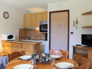Appartement Vars, 1 pièce, 4 personnes - FR-1-330B-178 في فار: مطبخ مع طاولة خشبية عليها لوحات