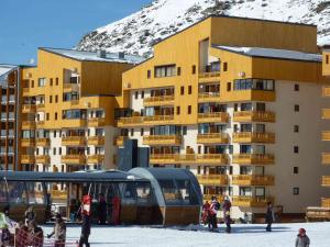 a building with people standing in the snow near a bus at Charmant Appartement Rénové - 4 Pers, Balcon Sud, Cœur de Val Thorens, Accès Pistes et Commerces - FR-1-637-7 in Val Thorens