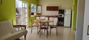 cocina con paredes verdes, mesa y sillas en Davies Apartment en Puerto Madryn