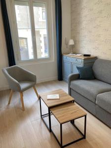 ein Wohnzimmer mit einem Sofa, einem Stuhl und einem Tisch in der Unterkunft Les Beaux Jours, Tours, le Duplex in Tours