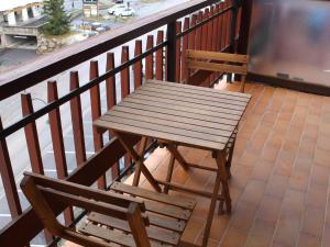une table en bois et deux chaises assises sur un balcon dans l'établissement Appartement Vars, 1 pièce, 6 personnes - FR-1-330B-184, à Vars