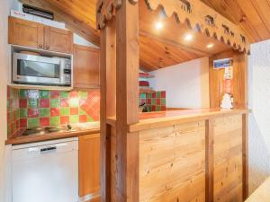 eine Küche mit Holzschränken und einer Mikrowelle in der Unterkunft Appartement Valmorel, 3 pièces, 4 personnes - FR-1-291-871 in Valmorel