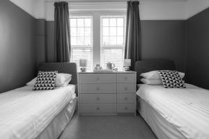 a bedroom with two beds and a dresser and a window at Millbrook Guest House in Swanage