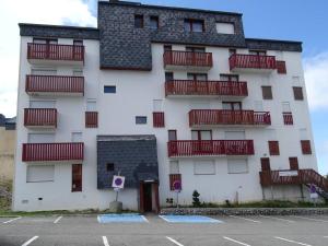 a white building with red balconies and a parking lot at Studio ski, 4 pers, parking gratuit, proche pistes - FR-1-602-97 in Arette