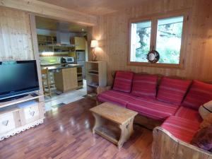 a living room with a red couch and a television at Studio Le Grand-Bornand, 1 pièce, 2 personnes - FR-1-458-153 in Le Grand-Bornand