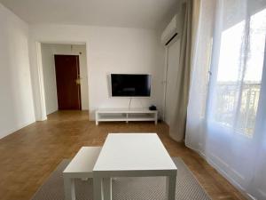 uma sala de estar com uma mesa branca e uma televisão em Petit cocon avec Balcon au centre de Marseille em Marselha