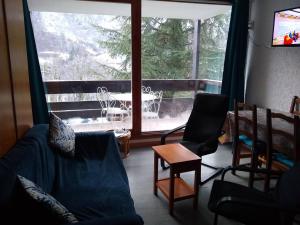 a living room with a couch and chairs and a large window at Studio Cauterets, 1 pièce, 4 personnes - FR-1-234-272 in Cauterets