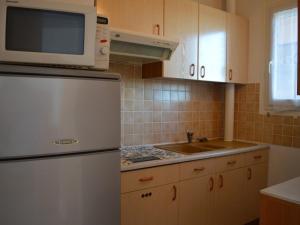La cuisine est équipée d'un réfrigérateur blanc et d'un four micro-ondes. dans l'établissement Appartement Saint-Cyprien, 1 pièce, 4 personnes - FR-1-225D-125, à Saint-Cyprien