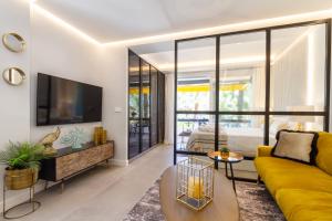 a living room with a yellow couch and a tv at MARBELLA BANUS SUITES - Golden Mile Carolina Park Suite Apartment in Marbella