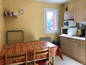 a kitchen with a table with chairs and a microwave at Studio 6 pers, à côté des pistes, parking & ascenseur, casier à skis, proche commerces - FR-1-602-101 in Arette +3 photos