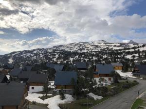 a village with snow covered mountains in the background at Studio 6 pers, à côté des pistes, parking & ascenseur, casier à skis, proche commerces - FR-1-602-101 in Arette