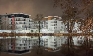 a building with a reflection in a body of water at Randez-View Apartment in Iława
