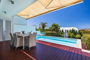 een patio met een tafel en stoelen naast een zwembad bij ELLE Design Villa by OCvillas in Albufeira