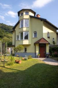 a yellow house with a red door in a yard at Riverside Villa Avo - Apartment AVO in Spodnja Idrija