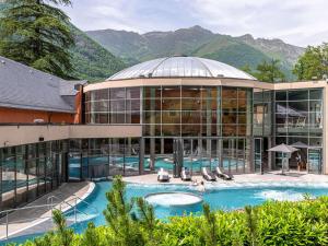 a large building with a swimming pool in front of it at Appartement Cauterets, 3 pièces, 4 personnes - FR-1-401-240 in Cauterets