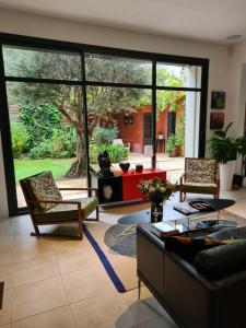 uma sala de estar com um sofá e cadeiras e uma grande janela em Suite indépendante avec 1 chambre et 1 bureau em Montpellier