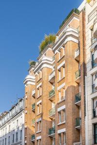 un grand bâtiment en briques avec des plantes au-dessus dans l'établissement Résidence Courcelle, à Levallois-Perret