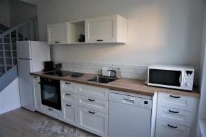 a kitchen with white cabinets and a sink and a microwave at Les Beaux Jours, Tours, le Duplex in Tours