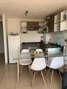 een keuken met een glazen tafel en witte stoelen bij Depto Costa Algarrobo Norte in Yeco