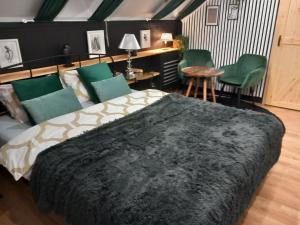 a bedroom with a large bed and green chairs at Pokoje Gościnne Magnolia Rooms in Serock