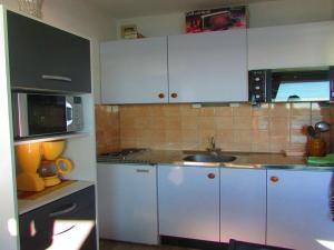 La cuisine est équipée de placards blancs, d'un évier et d'un four micro-ondes. dans l'établissement Studio Étel, 1 pièce, 3 personnes - FR-1-479-79, à Étel