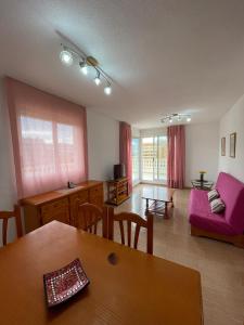 a living room with a table and a pink couch at Alpen 1 Voramar Playa Norte in Peniscola