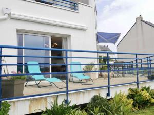 - un balcon avec des chaises bleues dans un bâtiment dans l'établissement Appartement Étel, 3 pièces, 5 personnes - FR-1-479-98, à Étel