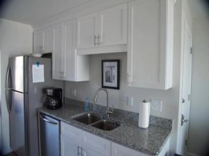 a kitchen with white cabinets and a sink and a refrigerator at A Beach Dream condo in Carolina Beach