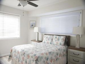 a white bedroom with a bed and two windows at A Beach Dream condo in Carolina Beach