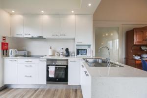 a kitchen with white cabinets and a sink at O Nosso Refúgio in Água de Pau